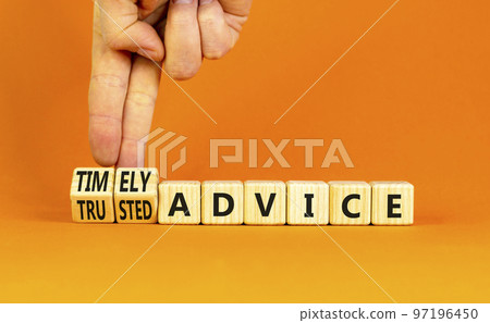 Timely or trusted advice symbol. Concept words Timely advice and Trusted advice on wooden cubes. Businessman hand. Beautiful orange background. Business timely or trusted advice concept. Copy space. 97196450