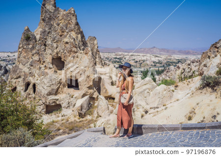Young woman exploring valley with rock formations and fairy caves near Goreme in Cappadocia Turkey Young woman exploring valley with rock formations and fairy caves near Goreme in Cappadocia Turkey 97196876