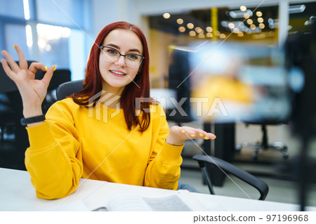 Female blogger with laptop recording video while sitting at office and talking about startup business. 97196968