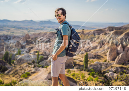 Young man exploring valley with rock formations and fairy caves near Goreme in Cappadocia Turkey Young man exploring valley with rock formations and fairy caves near Goreme in Cappadocia Turkey 97197148