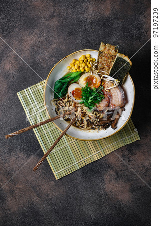 A Shoyu Ramen in white bowl on dark table top. Japanese cuisine meat noodle soup with chashu pork. Asian food A Shoyu Ramen in white bowl on dark table top. Japanese cuisine meat noodle soup with chashu pork. Asian food 97197239