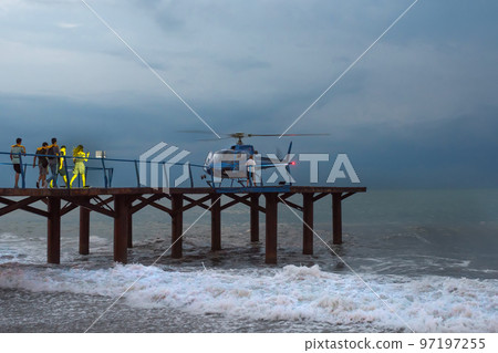 Rescuers head for a helicopter, in a gale. Night time 97197255