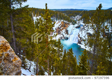 Yellowstone in winter at stunning lower falls through pine trees 97197396