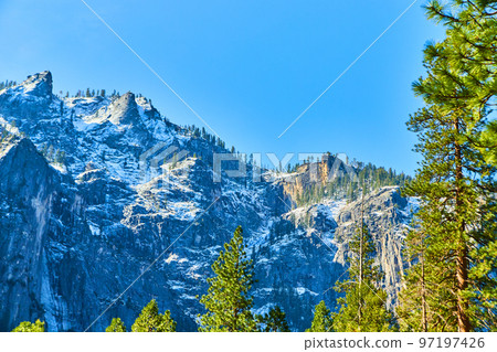 Yosemite snowy mountains viewed from forest in valley 97197426