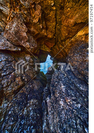 Tunnel of sharp rocks leading to ocean water 97197454