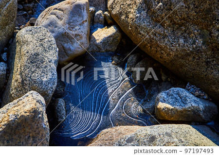 Unique and beautiful wavy ice formation detail between rocks Unique and beautiful wavy ice formation detail between rocks 97197493