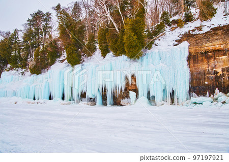 Icicles and ice formations blue frozen to rocky cliffs Icicles and ice formations blue frozen to rocky cliffs 97197921