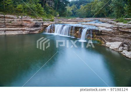 Forest behind a rocky river leading up to Cataract Falls and a deep river 97198124
