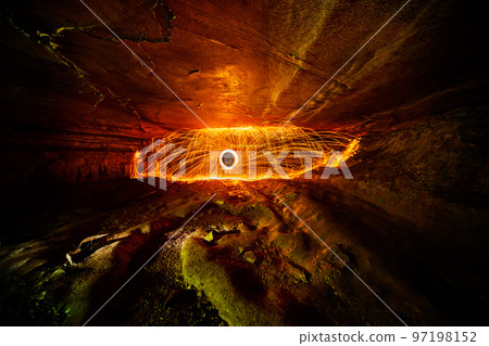 Fire dome and ring of orange sparks inside a wide but narrow cave with a smooth ceiling and a bumpy floor 97198152