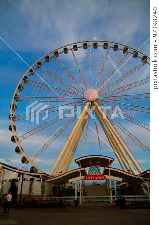 A ferris wheel begins to light up at twilight with no one in line to ride it 97198240