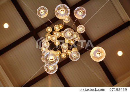Worm's eye view of a glass chandelier made of glass globes on a black and white checked ceiling Worm's eye view of a glass chandelier made of glass globes on a black and white checked ceiling 97198459
