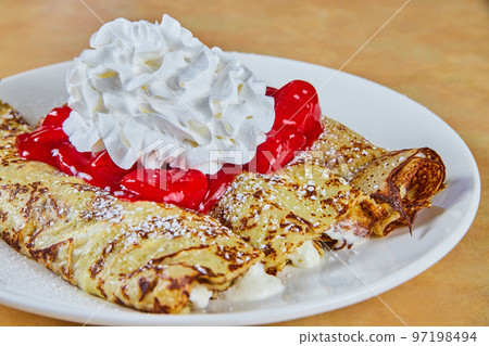 Breakfast of three crepes with strawberry compote and whipped cream 97198494