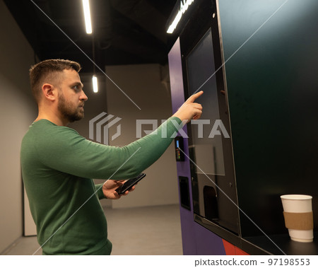 Caucasian man chooses coffee in a self-service machine. 97198553