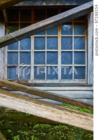Old building with grime covered windows and a mossy exterior 97198554
