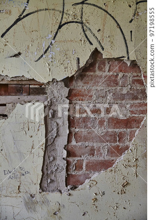 Old dilapidated concrete wall peeling away to reveal bricks with black graffiti background 97198555