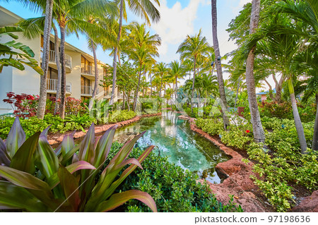 Resort in tropics with river, lodging, and palm trees 97198636