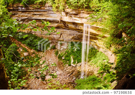 Curved canyon cliffs with stream of water pouring into rocks 97198638