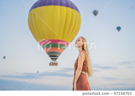 Tourist woman looking at hot air balloons in Cappadocia, Turkey. Happy Travel in Turkey concept. Woman on a mountain top enjoying wonderful view 97198763