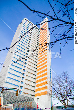 A tall skyscraper that's half blue and half orange in winter on a clear blue sky 97198780