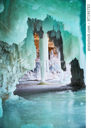 Tunnel of green and blue ice in cave leading to large icicle 97198783