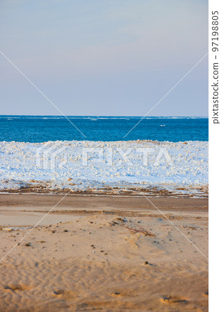 Vertical layers on beach of sky, water, ice, and sand 97198805