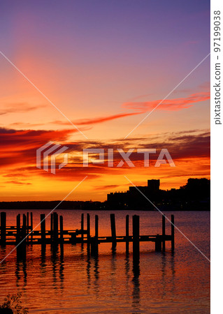 Golden red sunrise with docks sitting in a rive with ripples of water 97199038