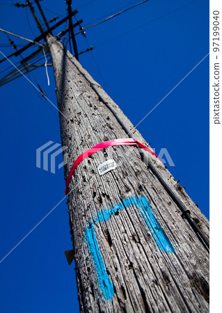 Colorful wooden telephone pole reaching into a blue sky 97199040