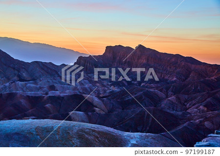 Death Valley at dawn with golden light silhouetting mountains of color Death Valley at dawn with golden light silhouetting mountains of color 97199187