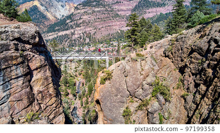 Aerial of deep canyon in the mountains with view of river and walking bridge crossing over Aerial of deep canyon in the mountains with view of river and walking bridge crossing over 97199358