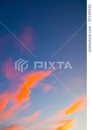 Neon orange thin wispy clouds on a blue sky Neon orange thin wispy clouds on a blue sky 97199385