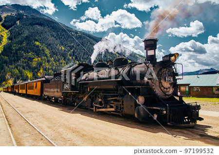 Vintage locomotive train up close in town against mountains Vintage locomotive train up close in town against mountains 97199532