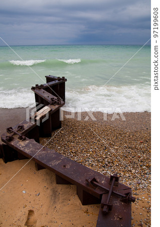 Zigzagging pier juts out into the lake and separates a rocky beach from a sandy beach Zigzagging pier juts out into the lake and separates a rocky beach from a sandy beach 97199608