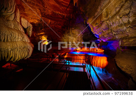 Tour path through Indiana underground cave with waterfall lite by blue and orange lights Tour path through Indiana underground cave with waterfall lite by blue and orange lights 97199638