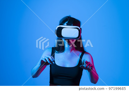 Brunette woman in a black top wearing virtual reality goggles in modern coworking studio. 97199685