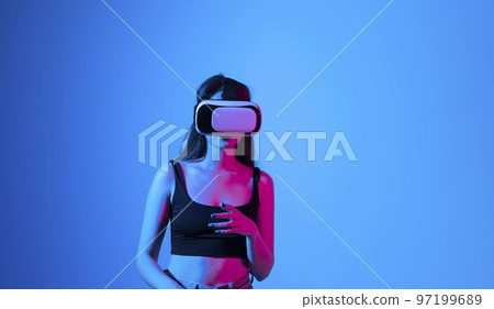 Brunette woman wearing virtual vr goggles. Young famale in a black top wearing virtual reality headset. VR concept. 97199689