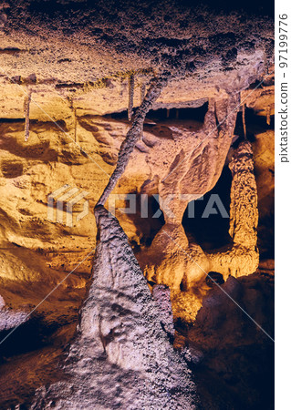 Vertical of unusual cave formations stalagmites and stalactites joining 97199776