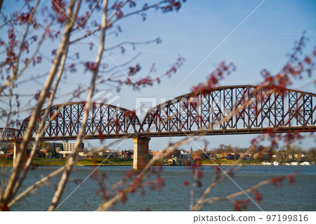 Steel bridge going over a large river outside Louisville through the branches of trees Steel bridge going over a large river outside Louisville through the branches of trees 97199816