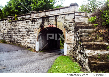 Small road going under stone tunnel with stone steps to the top Small road going under stone tunnel with stone steps to the top 97199865