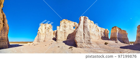 Panorama of white and beige vertical rock monuments against blue sky Panorama of white and beige vertical rock monuments against blue sky 97199876