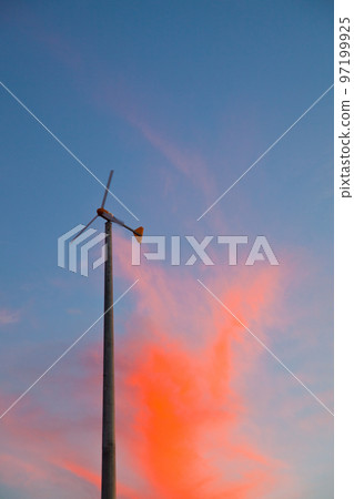 Windmill on a mostly blue sky with neon orange clouds 97199925