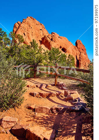 Stone steps in desert path with wood fence and large red rocks against blue sky Stone steps in desert path with wood fence and large red rocks against blue sky 97199975