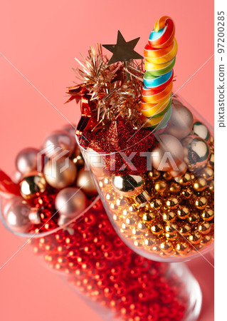 Studio shot of Christmas decorations in a glass against pink background 97200285