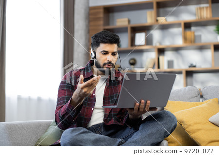 Closeup of young student man in wireless headset watching online lesson on laptop Closeup of young student man in wireless headset watching online lesson on laptop 97201072