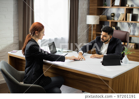 Young red hair businesswoman giving an illegal money or bribe money to her bearded business dealer 97201191