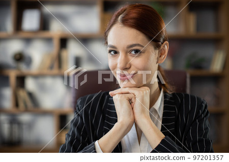 Front view face of cheerful attractive young red hair woman in formal clothing sitting at office 97201357