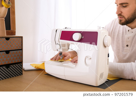 Fashion designer sewing new clothes with machine in studio, closeup Fashion designer sewing new clothes with machine in studio, closeup 97201579