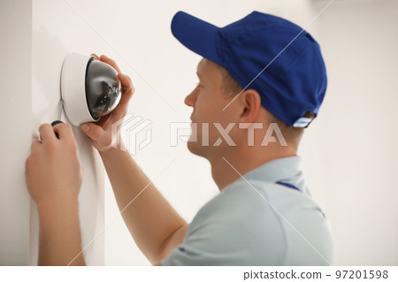 Technician installing CCTV camera on wall, closeup Technician installing CCTV camera on wall, closeup 97201598