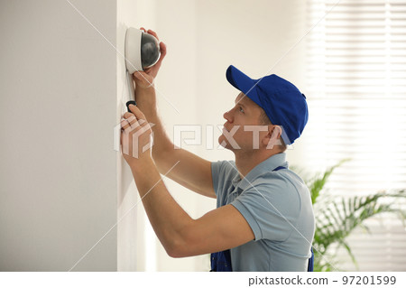 Technician installing CCTV camera on wall indoors Technician installing CCTV camera on wall indoors 97201599
