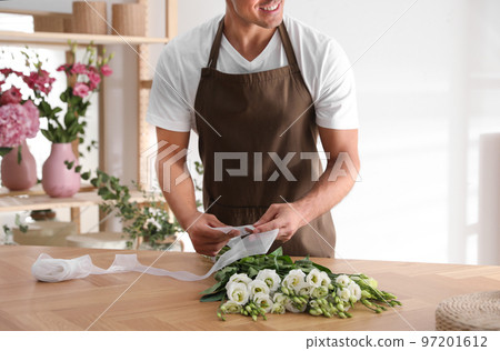 Florist making beautiful bouquet at table in workshop, closeup 97201612