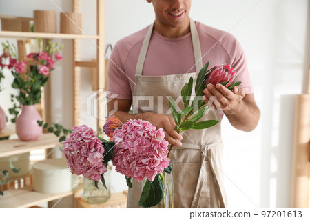 Florist with beautiful flowers in workshop, closeup Florist with beautiful flowers in workshop, closeup 97201613